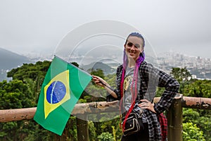 A girl with purple braids on her head waving a Brazilian flag photo