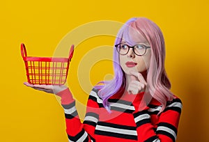 Girl with purple hair and red sweater hold shopping basket