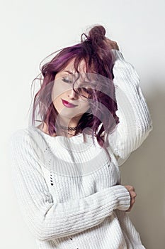 girl with purple hair and tattoos on his body posing in white shirt on gray background. Perfect woman in white dress sitting