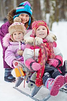 Girl pushes sledges with two younger children