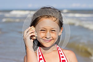 Girl put to the ear sea shell