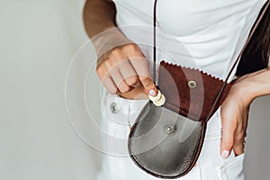 Girl puts a coin in the leather purse.