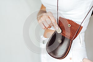 Girl puts a coin in the leather purse.