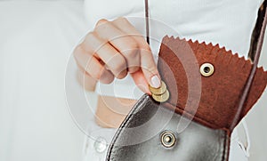 Girl puts a coin in the leather purse.