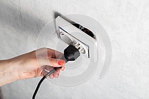 The girl puts the electric plug into a broken socket. Risk of electric shock, close-up