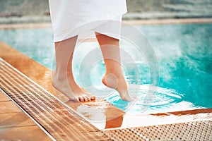 A girl puts her foot in a pool with hot thermal water, a wellness vacation at hot springs