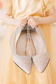 The girl puts on her mother`s shoes. Mother`s shoes in children`s hands