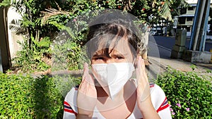 Girl puts on a medical mask to prevent virus outdoors.