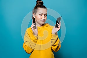 Girl puts a smartphone to her ear and looks at the old cell telephone with a sad smile