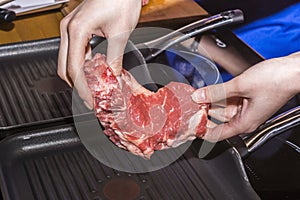 Girl puts a steak on a fring pan photo