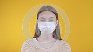 Girl puts on and takes off a medical mask on a yellow background