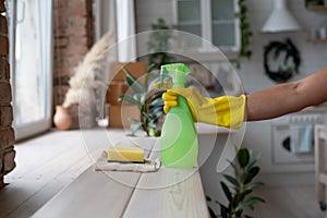 The girl puts on a yellow rubber glove. Hand holding green spray bottle
