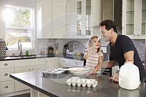 Girl putting cake mix on dadï¿½s nose while they bake together