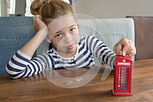 Girl putting coin to the coin box look like traditional british call box, saving money concept