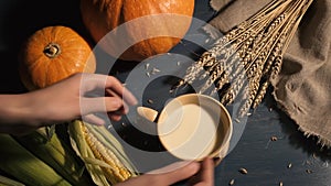 The girl is putting a cup of milk on the table. Still Life of Pumpkins and Wheat on the Background. concept of harvest