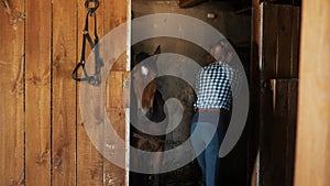 Girl Putting Fresh Hays In The Horse Stall - A Brown Horse Standing In The Stall
