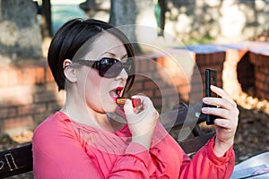 Girl Putting Lipstick on Her Lips and Using Cellphone Instead Mirror