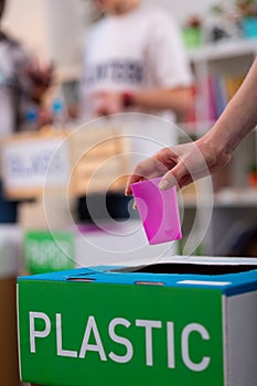 Girl putting pink plastic cup into box while sorting waste photo