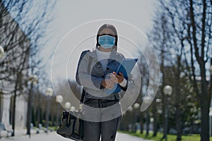 Girl putting on a protective mask to avoid contagion while walking down the street. Coronavirus concept