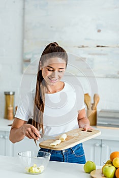 Girl putting sliced banana in glass bowl near fruits