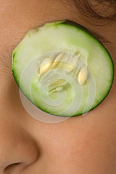 Girl putting sliced cucumber on eye