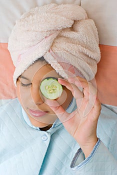 Girl putting sliced cucumber on her eye