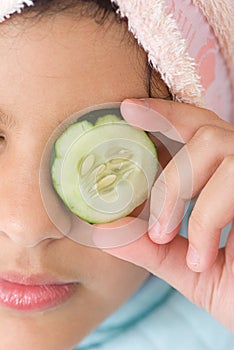 Girl putting sliced cucumber on her eye