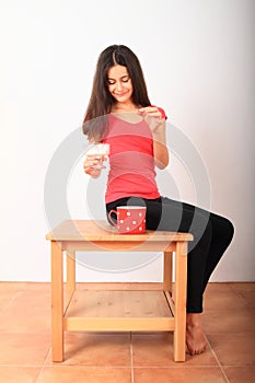 Girl putting sugar into cup of tea