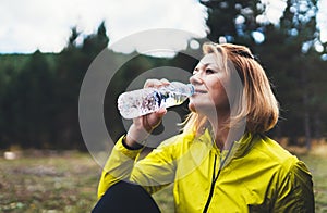 Girl quenches thirst after training fitness. Smile person drinking water from plastic bottles relax after exercising sport outdoor