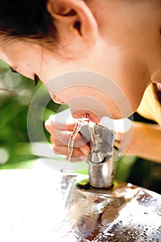 Girl quenching thirst at water cooler photo