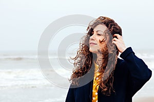 Girl rain sea wind winter portrait woman smile spring coat long hair curly mood shore snow beach