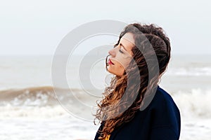 Girl rain sea wind winter portrait woman smile spring coat long hair curly mood shore snow beach