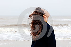 Girl rain sea wind winter portrait woman smile spring coat long hair curly mood shore snow beach