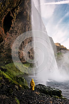 Girl in raincoat and waterfall. Iceland