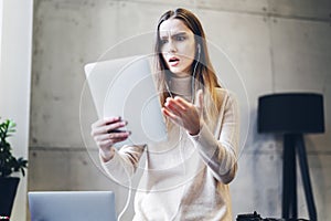 Girl reacting emotionally on internet content in social media. Female reading breaking news on screen of tablet. Shocking and