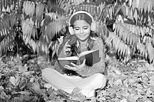 Girl read book on autumn day. Little child enjoy learning in autumn park. Kid study with book. Autumn literature concept