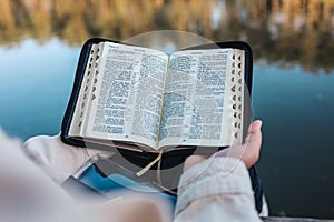 Girl reading the Bible on the river bank