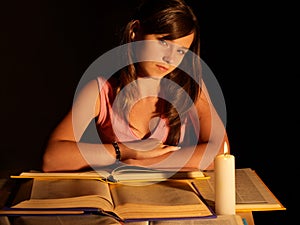 Girl reading book with candle.
