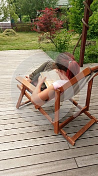 Girl reading book in deck chair