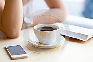 Girl reading book and drinking coffee at cafe