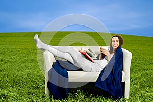 Girl reading book and drinking coffee on the couch