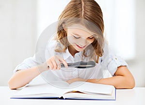 Girl reading book with magnifier at school