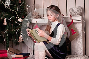 Girl reading book among the new year decorations