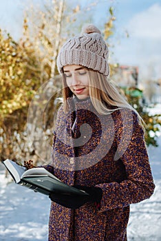 Girl reading book outdoors in winter