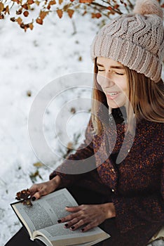 Girl reading book outdoors in winter