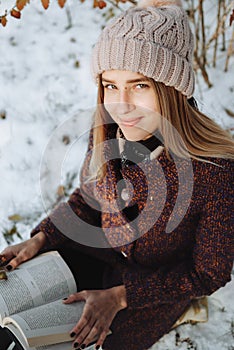 Girl reading book outdoors in winter