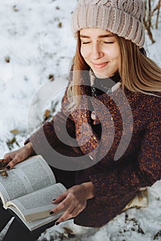 Girl reading book outdoors in winter