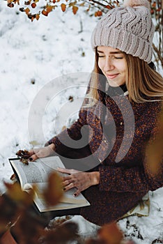 Girl reading book outdoors in winter