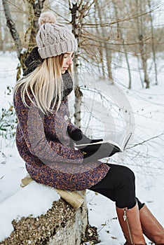 Girl reading book outdoors in winter