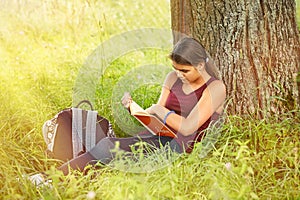 The girl is reading a book in the park in the summer